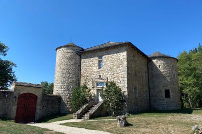 Miniature Location salle Montregard (Haute-Loire) - Château de Marcoux #7 Cour extérieure avec table et chaises en métal, entourée de murs en pierre, d'un bâtiment en pierre et d'arbres.