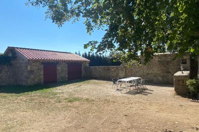 Miniature Location salle Montregard (Haute-Loire) - Château de Marcoux #12 Cour extérieure avec table et chaises en métal, entourée de murs en pierre, d'un bâtiment en pierre et d'arbres.