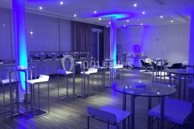 Salle de réception avec tables rondes dressées, décorées de nappes colorées et centres de table floraux.