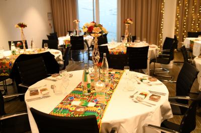 Salle de réception avec tables rondes dressées, décorées de nappes colorées et centres de table floraux.