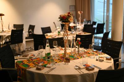 Salle de réception avec tables rondes dressées, décorées de nappes colorées et centres de table floraux.