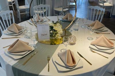 Salle de réception avec tables rondes dressées, décorées de nappes colorées et centres de table floraux.