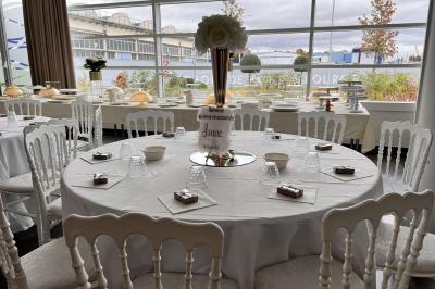 Salle de réception avec tables rondes dressées, décorées de nappes colorées et centres de table floraux.