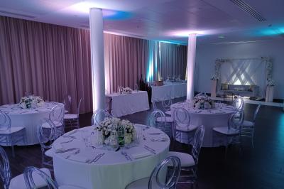 Salle de réception avec tables rondes dressées, décorées de nappes colorées et centres de table floraux.