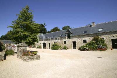 Salle de restaurant avec murs en pierre, tables en bois dressées, chaises bleues et un tableau de flamant rose au mur.