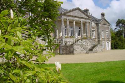 Salle de restaurant avec murs en pierre, tables en bois dressées, chaises bleues et un tableau de flamant rose au mur.