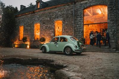Salle de restaurant avec murs en pierre, tables en bois dressées, chaises bleues et un tableau de flamant rose au mur.