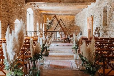 Salle de restaurant avec murs en pierre, tables en bois dressées, chaises bleues et un tableau de flamant rose au mur.
