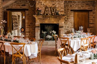 Salle de restaurant avec murs en pierre, tables en bois dressées, chaises bleues et un tableau de flamant rose au mur.
