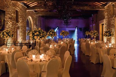 Intérieur d'une serre lumineuse avec un toit en verre, des lustres suspendus et un sol réfléchissant.