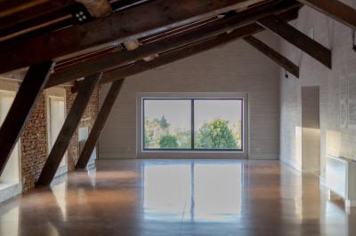 Intérieur d'une serre lumineuse avec un toit en verre, des lustres suspendus et un sol réfléchissant.