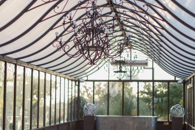 Intérieur d'une serre lumineuse avec un toit en verre, des lustres suspendus et un sol réfléchissant.