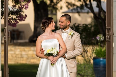 Un couple en tenue de mariage s'enlace dans un champ entouré d'oliviers sous une lumière douce.