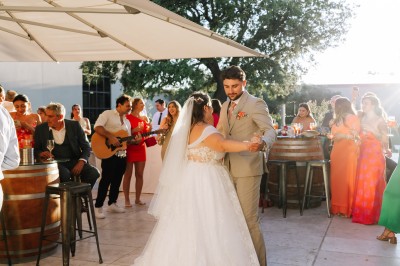 Un couple en tenue de mariage s'enlace dans un champ entouré d'oliviers sous une lumière douce.
