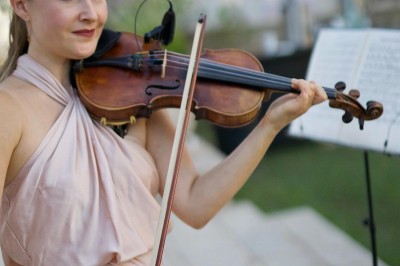 Un couple en tenue de mariage s'enlace dans un champ entouré d'oliviers sous une lumière douce.