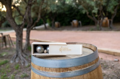 Un couple en tenue de mariage s'enlace dans un champ entouré d'oliviers sous une lumière douce.