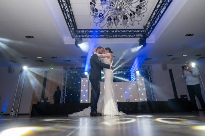 Un couple en tenue de mariage s'enlace dans un champ entouré d'oliviers sous une lumière douce.