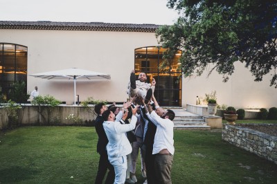 Un couple en tenue de mariage s'enlace dans un champ entouré d'oliviers sous une lumière douce.
