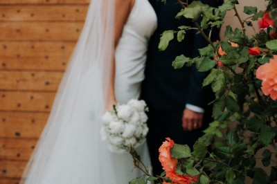 Un couple en tenue de mariage s'enlace dans un champ entouré d'oliviers sous une lumière douce.