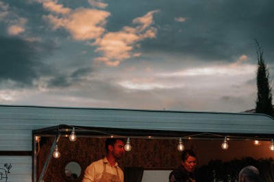 Un couple en tenue de mariage s'enlace dans un champ entouré d'oliviers sous une lumière douce.