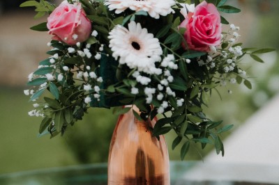 Un couple en tenue de mariage s'enlace dans un champ entouré d'oliviers sous une lumière douce.