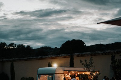 Un couple en tenue de mariage s'enlace dans un champ entouré d'oliviers sous une lumière douce.