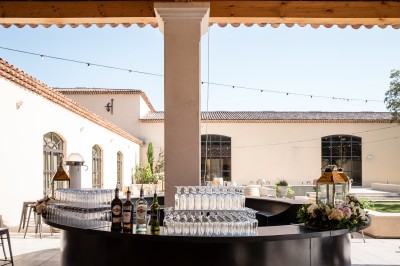 Un couple en tenue de mariage s'enlace dans un champ entouré d'oliviers sous une lumière douce.