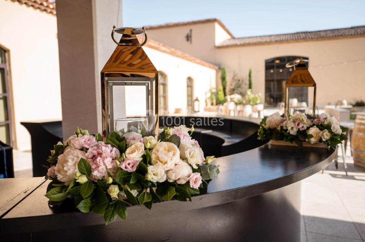 Deux lanternes dorées décorées de fleurs blanches et roses sur un comptoir courbé en extérieur.
