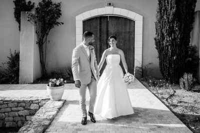 Un couple en tenue de mariage s'enlace dans un champ entouré d'oliviers sous une lumière douce.