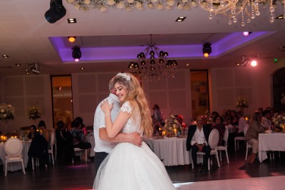 Un couple en tenue de mariage s'enlace dans un champ entouré d'oliviers sous une lumière douce.