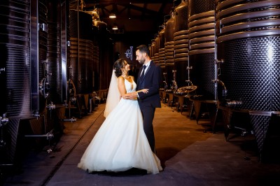 Un couple en tenue de mariage s'enlace dans un champ entouré d'oliviers sous une lumière douce.