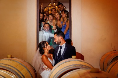 Un couple en tenue de mariage s'enlace dans un champ entouré d'oliviers sous une lumière douce.