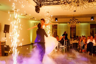 Un couple en tenue de mariage s'enlace dans un champ entouré d'oliviers sous une lumière douce.