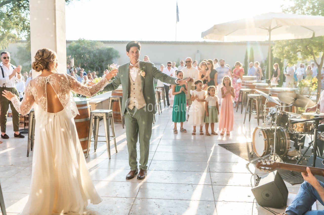 Un couple danse en extérieur lors d'une réception, entouré d'invités et d'enfants sous une lumière ensoleillée.