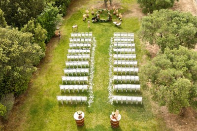 Un couple en tenue de mariage s'enlace dans un champ entouré d'oliviers sous une lumière douce.