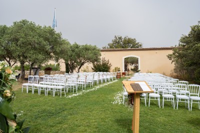 Un couple en tenue de mariage s'enlace dans un champ entouré d'oliviers sous une lumière douce.