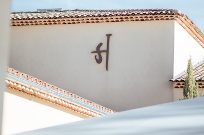 Un couple en tenue de mariage s'enlace dans un champ entouré d'oliviers sous une lumière douce.