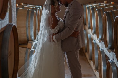 Un couple en tenue de mariage s'enlace dans un champ entouré d'oliviers sous une lumière douce.