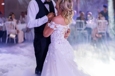 Un couple en tenue de mariage s'enlace dans un champ entouré d'oliviers sous une lumière douce.