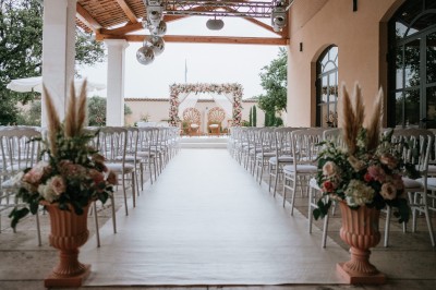 Un couple en tenue de mariage s'enlace dans un champ entouré d'oliviers sous une lumière douce.