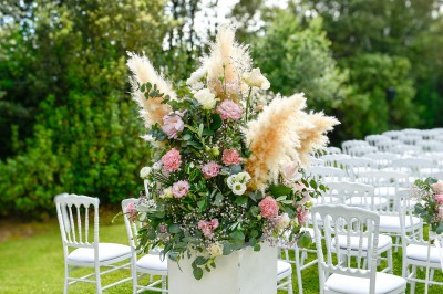 Un couple en tenue de mariage s'enlace dans un champ entouré d'oliviers sous une lumière douce.