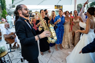 Un couple en tenue de mariage s'enlace dans un champ entouré d'oliviers sous une lumière douce.