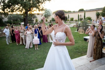 Un couple en tenue de mariage s'enlace dans un champ entouré d'oliviers sous une lumière douce.