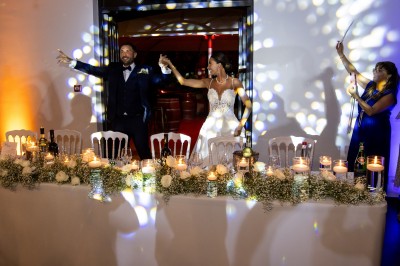 Un couple en tenue de mariage s'enlace dans un champ entouré d'oliviers sous une lumière douce.