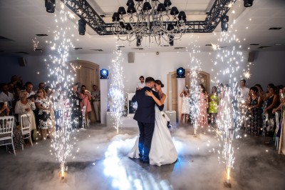 Un couple en tenue de mariage s'enlace dans un champ entouré d'oliviers sous une lumière douce.