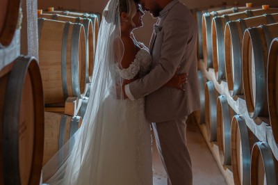 Un couple en tenue de mariage s'enlace dans un champ entouré d'oliviers sous une lumière douce.