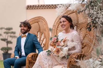 Un couple en tenue de mariage s'enlace dans un champ entouré d'oliviers sous une lumière douce.