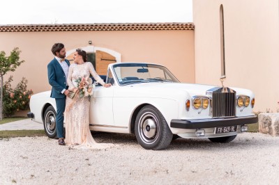 Un couple en tenue de mariage s'enlace dans un champ entouré d'oliviers sous une lumière douce.