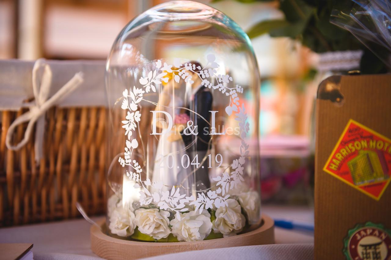 Cloche en verre décorative contenant des roses blanches et gravée des initiales ’D & L’ avec une date.