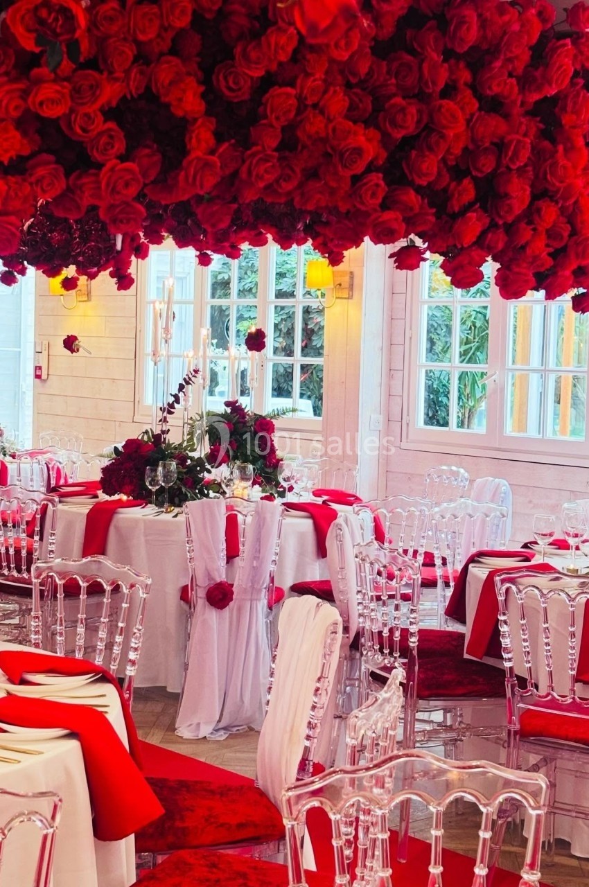 Location salle Hem (Nord) - Le Comte #15 Salle de réception décorée de roses rouges, tables dressées avec nappes blanches et chaises transparentes.